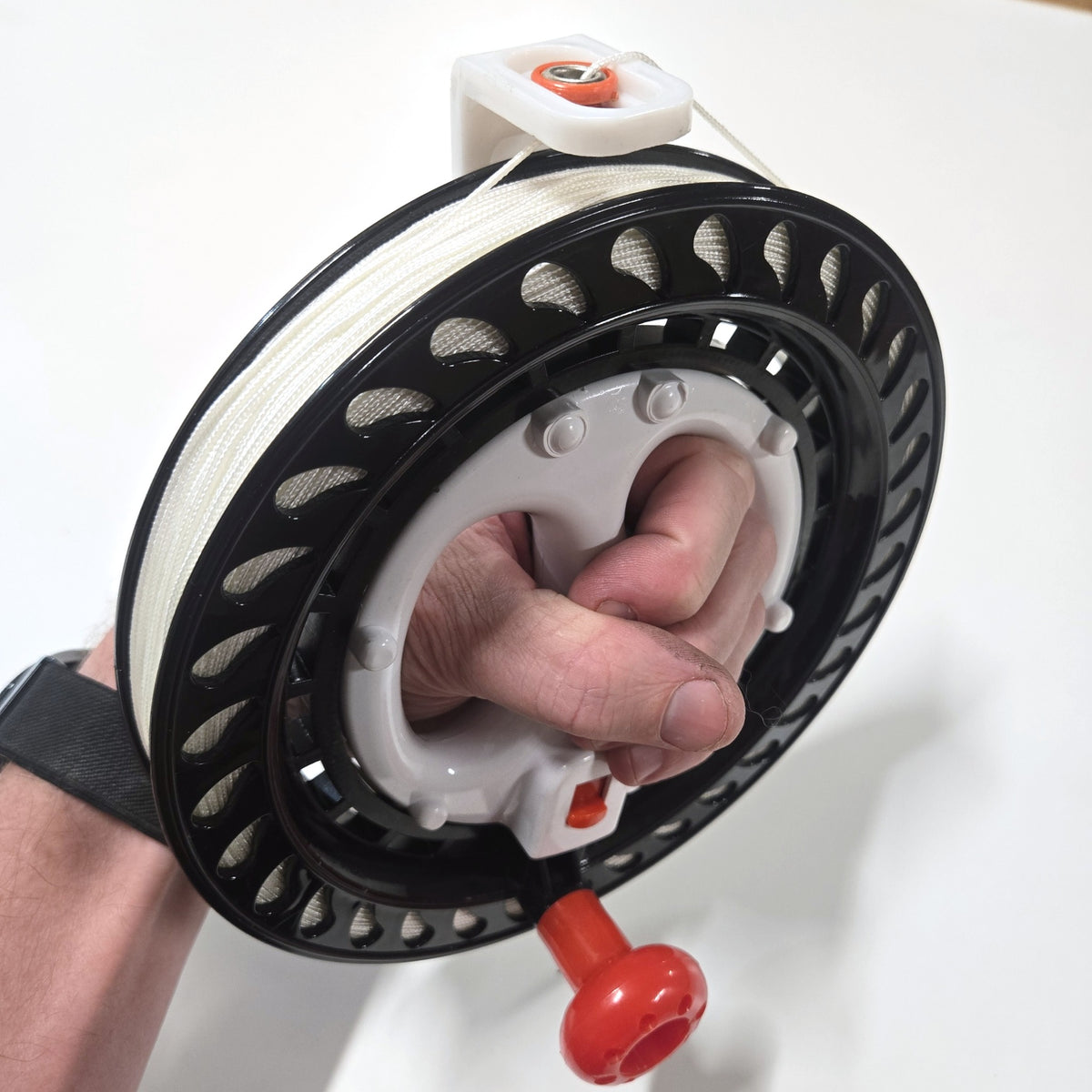Side view of the BruteLine 150m fully spooled winder in hand, showing the white braided line and the line guide