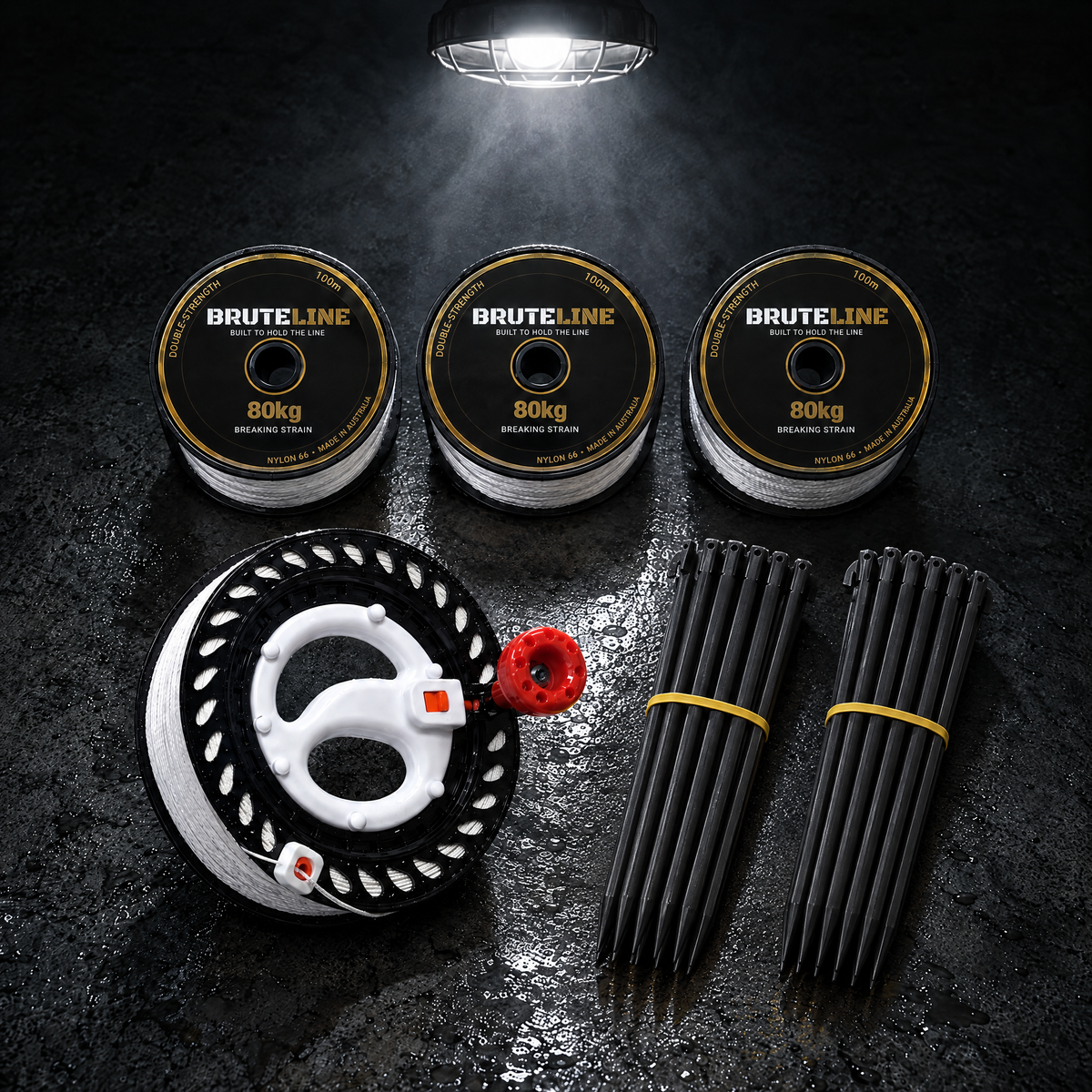 BruteLine Setout Kit laid out on concrete: three 100m reels, two packs of black ground pegs and the 150m fully spooled winder
