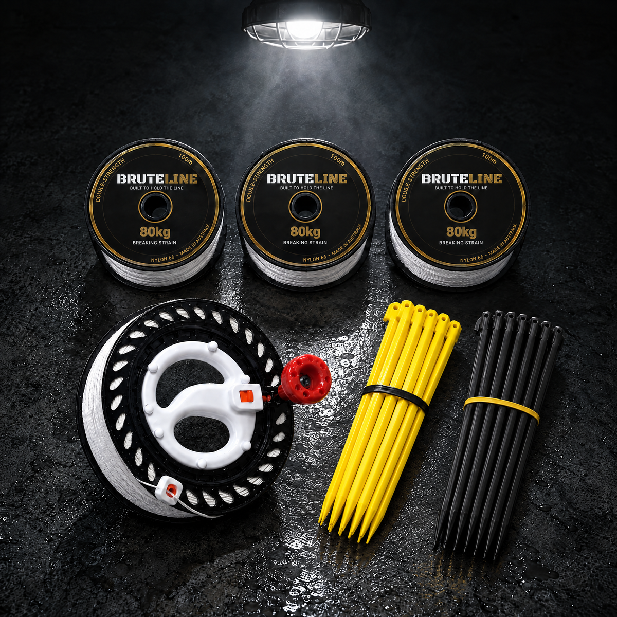 BruteLine Setout Kit laid out on concrete: three 100m reels, a pack of yellow and a pack of black ground pegs and the 150m fully spooled winder