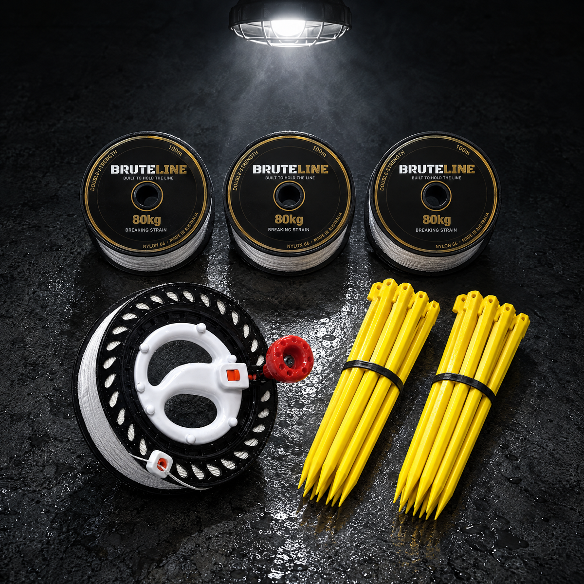 BruteLine Setout Kit laid out on concrete: three 100m reels, two packs of yellow ground pegs and the 150m fully spooled winder